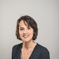Jessica Kaiser hat kinnlanges dunkelbraunes Haar, sie trägt eine Silberkette, ein graues Oberteil und ein grau-schwarzes Jackett.